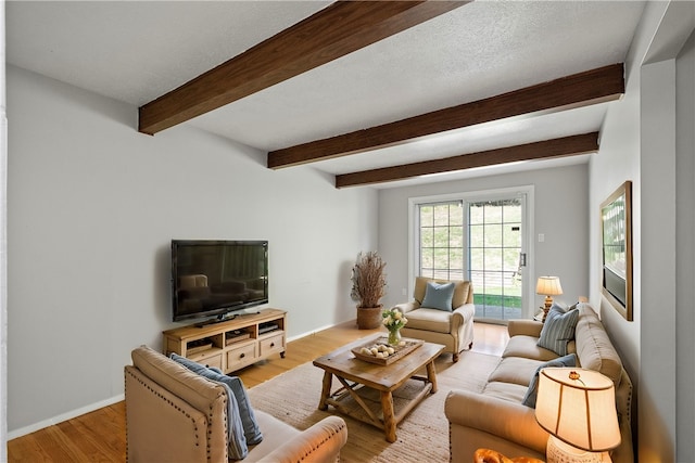 living room with beamed ceiling, light hardwood / wood-style flooring, and a textured ceiling