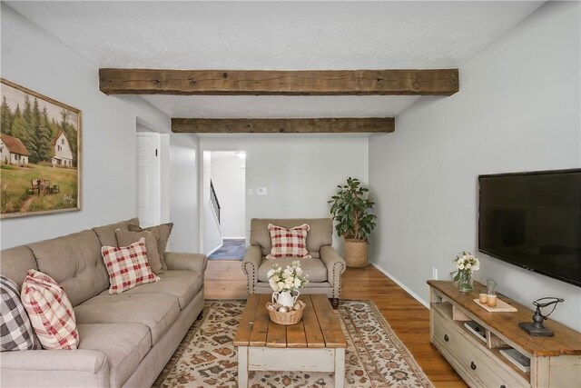 living room with beamed ceiling, light hardwood / wood-style flooring, and a textured ceiling