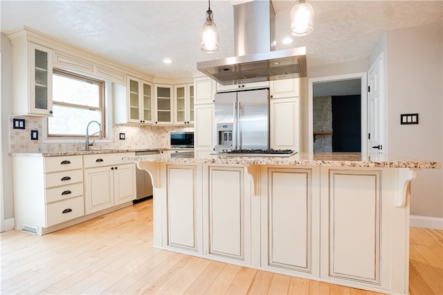 kitchen featuring a kitchen island, appliances with stainless steel finishes, decorative light fixtures, and island exhaust hood