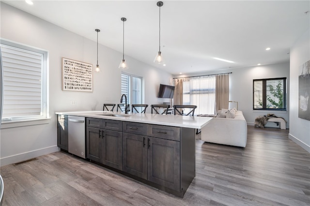 kitchen featuring dark brown cabinetry, sink, stainless steel dishwasher, decorative light fixtures, and light wood-type flooring