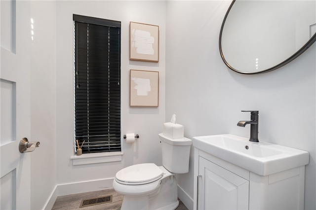 bathroom with vanity, toilet, and hardwood / wood-style flooring