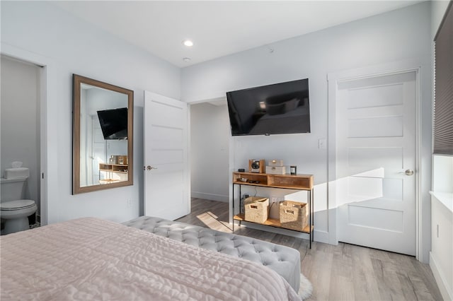 bedroom featuring light wood-type flooring and ensuite bath