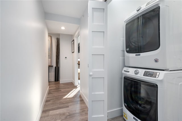 laundry area featuring stacked washer / drying machine and light wood-type flooring