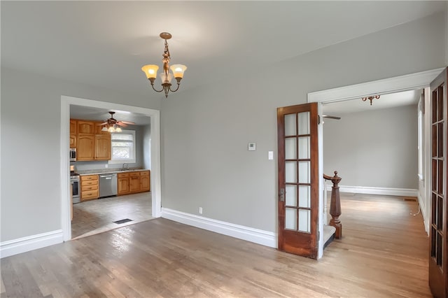 interior space featuring ceiling fan with notable chandelier, light wood-type flooring, sink, and french doors