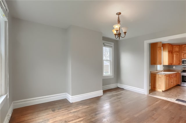 unfurnished dining area featuring light hardwood / wood-style flooring and a notable chandelier