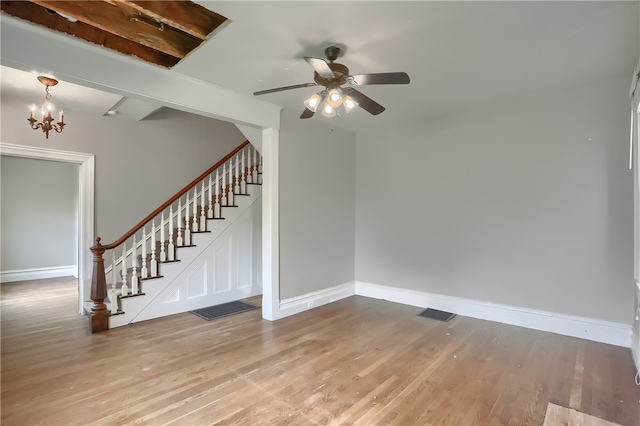 interior space featuring ceiling fan with notable chandelier and light hardwood / wood-style flooring