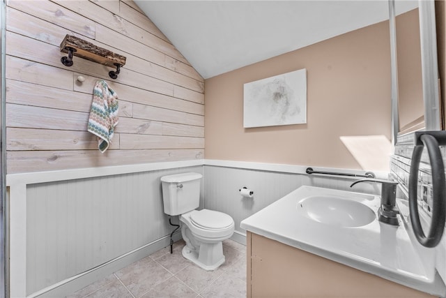 bathroom with wooden walls, vaulted ceiling, vanity, and toilet