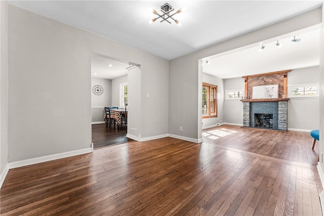 unfurnished living room featuring hardwood / wood-style flooring, a healthy amount of sunlight, and a stone fireplace