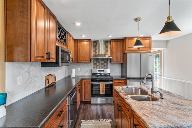 kitchen featuring sink, decorative light fixtures, dark wood-type flooring, wall chimney range hood, and appliances with stainless steel finishes