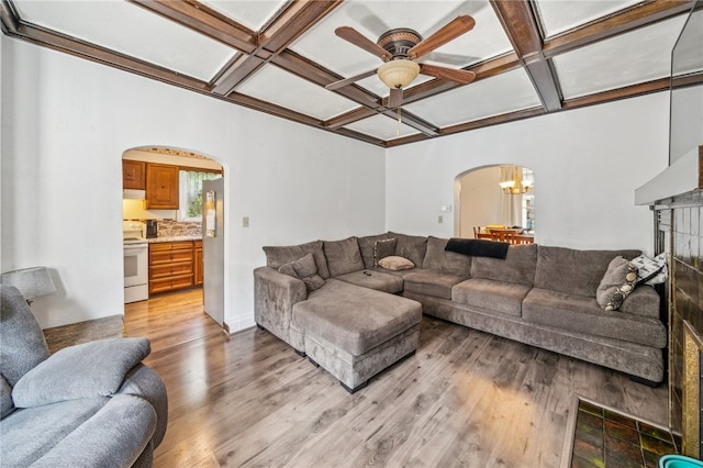 living room with light hardwood / wood-style floors, beamed ceiling, coffered ceiling, and ceiling fan