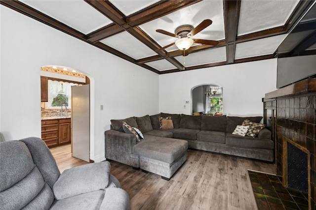 living room featuring coffered ceiling, a tiled fireplace, hardwood / wood-style flooring, and ceiling fan