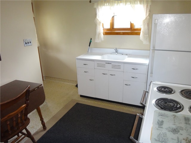 kitchen with white appliances, light tile patterned flooring, sink, and white cabinets