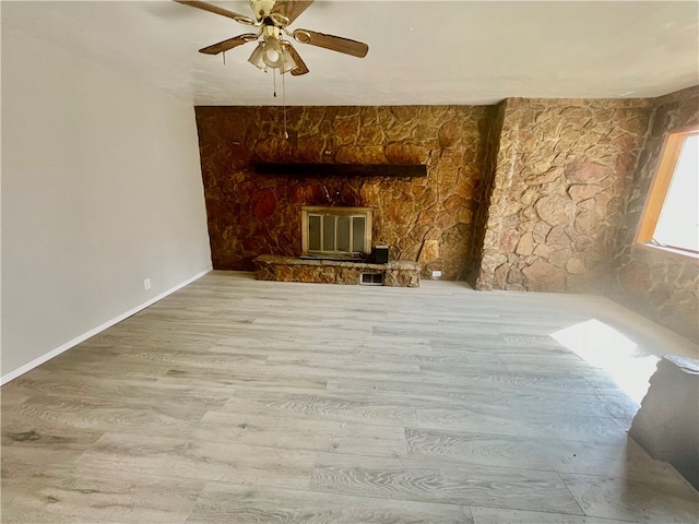 unfurnished living room featuring light hardwood / wood-style floors, ceiling fan, and a fireplace