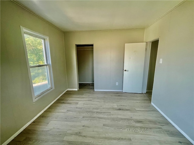 empty room featuring ornamental molding, a wealth of natural light, and light hardwood / wood-style floors