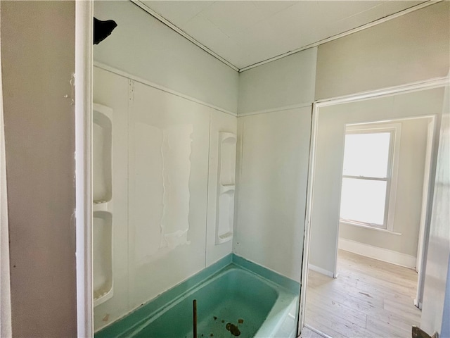 bathroom featuring washtub / shower combination and wood-type flooring