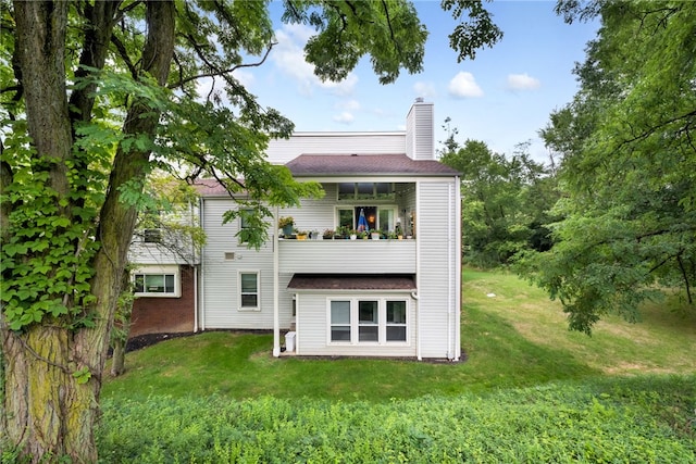 rear view of property featuring a balcony and a lawn