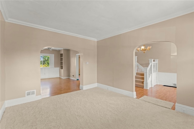 spare room featuring wood-type flooring, crown molding, and a chandelier