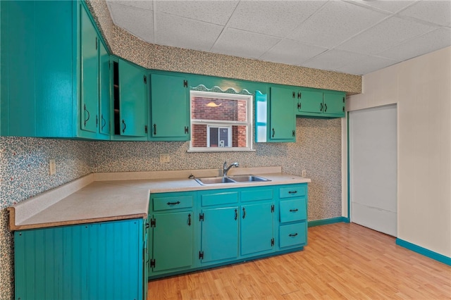 kitchen with decorative backsplash, a drop ceiling, sink, and light hardwood / wood-style flooring