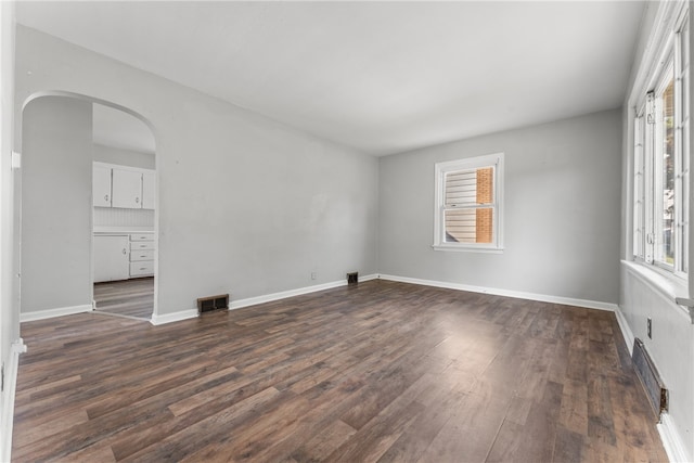 unfurnished room featuring a healthy amount of sunlight and dark hardwood / wood-style flooring