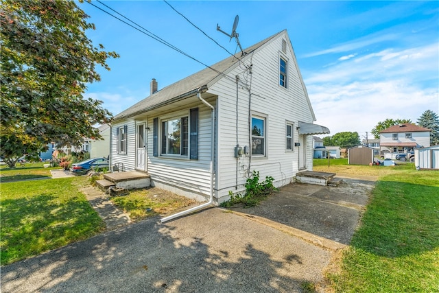 view of side of home with a storage shed and a lawn