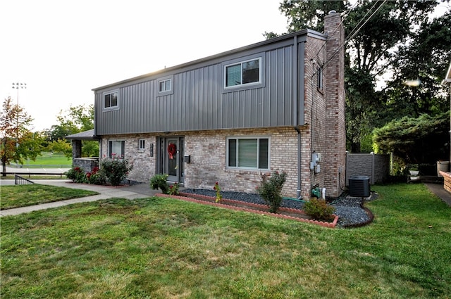 view of front of house featuring a front lawn and central AC