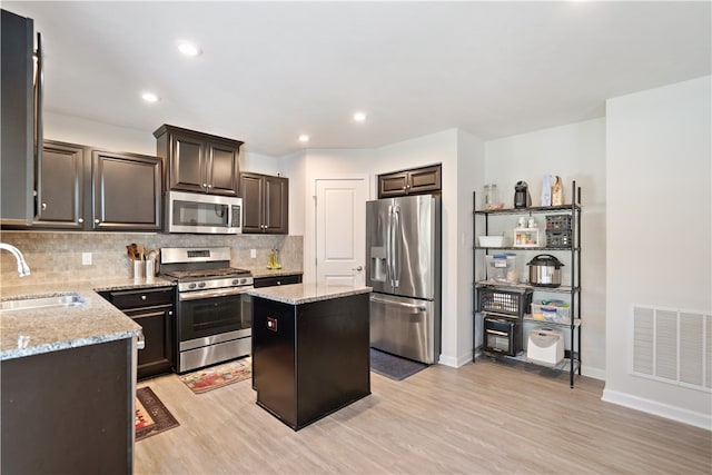 kitchen featuring light hardwood / wood-style floors, a center island, sink, stainless steel appliances, and light stone countertops