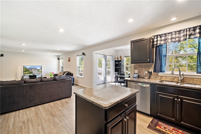 kitchen featuring sink, stainless steel dishwasher, backsplash, a center island, and light wood-type flooring