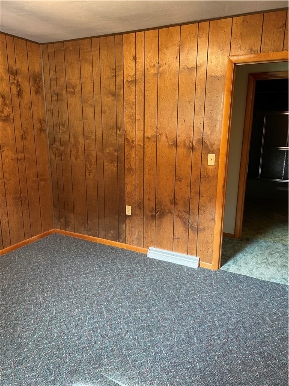 unfurnished room with carpet and wooden walls