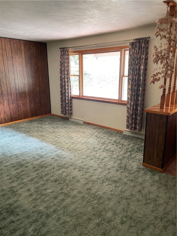 carpeted empty room with wooden walls and baseboard heating