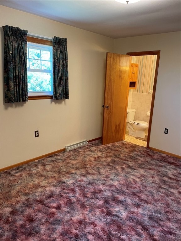 unfurnished bedroom featuring ensuite bath, carpet flooring, and a baseboard heating unit