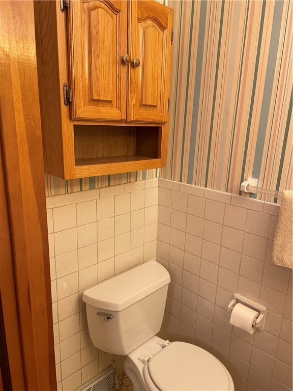 bathroom with tile walls and toilet