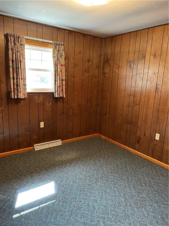 carpeted spare room featuring wooden walls