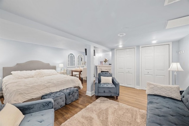 bedroom featuring multiple closets, a fireplace, and hardwood / wood-style flooring