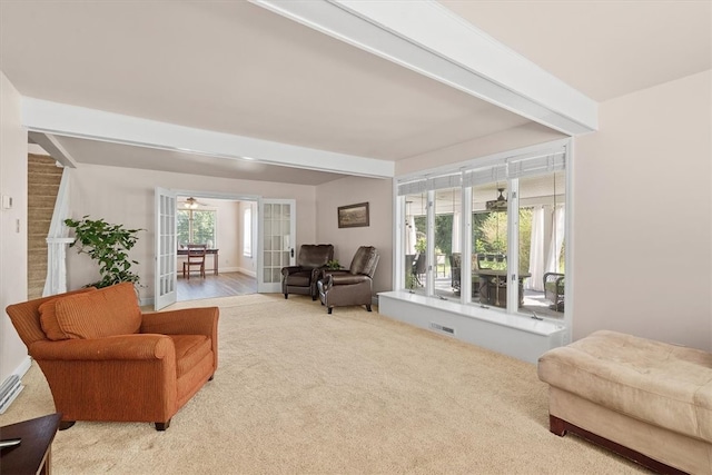 living room featuring beamed ceiling, french doors, and carpet flooring