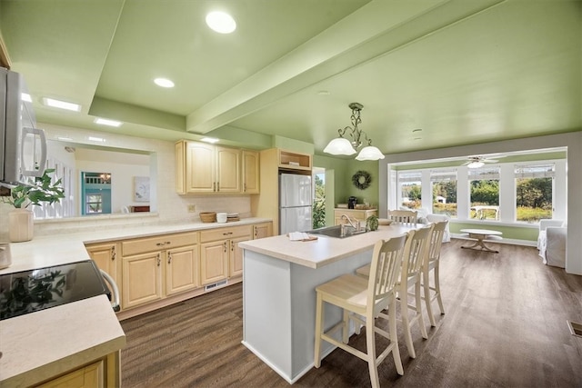 kitchen with a center island with sink, dark hardwood / wood-style floors, hanging light fixtures, a breakfast bar, and white appliances