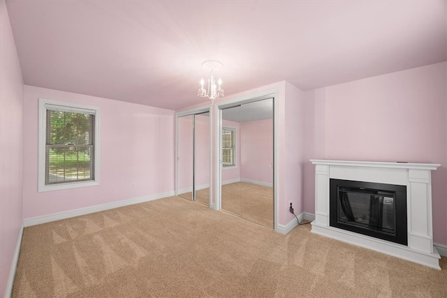 unfurnished living room featuring light colored carpet and a notable chandelier