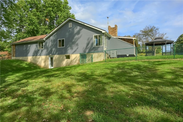 back of property featuring a gazebo and a lawn