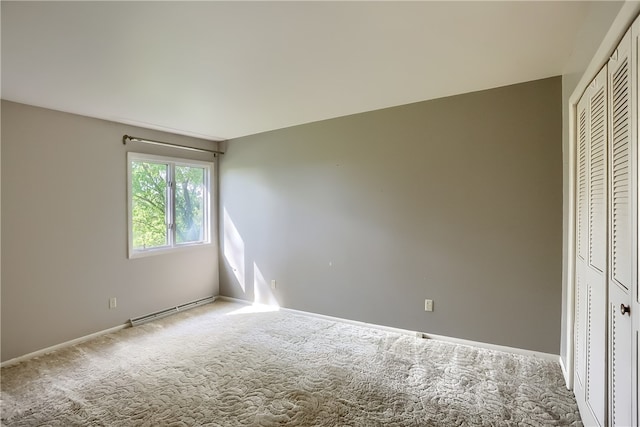 unfurnished bedroom featuring carpet, baseboard heating, and a closet