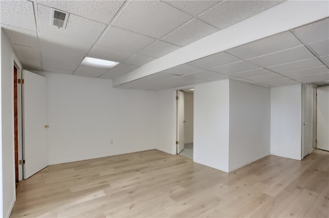 basement featuring light hardwood / wood-style flooring and a paneled ceiling