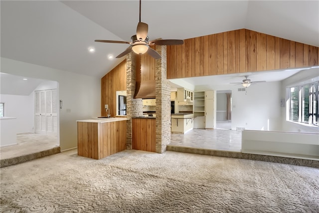 kitchen with lofted ceiling, wood walls, light carpet, and ceiling fan