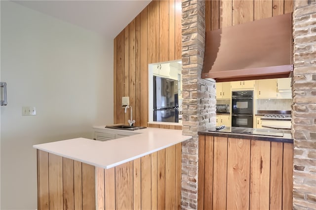 kitchen featuring wooden walls, sink, kitchen peninsula, and black appliances