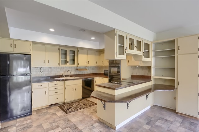 kitchen featuring tasteful backsplash, kitchen peninsula, black appliances, cream cabinets, and sink