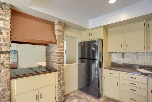 kitchen with decorative backsplash, fridge, black electric stovetop, and cream cabinetry