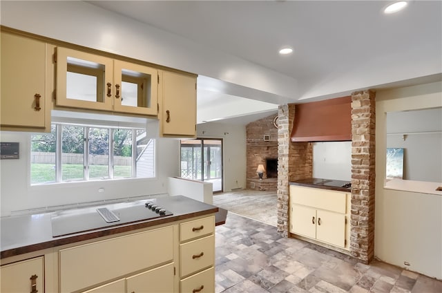 kitchen with cream cabinets, a large fireplace, and ornate columns