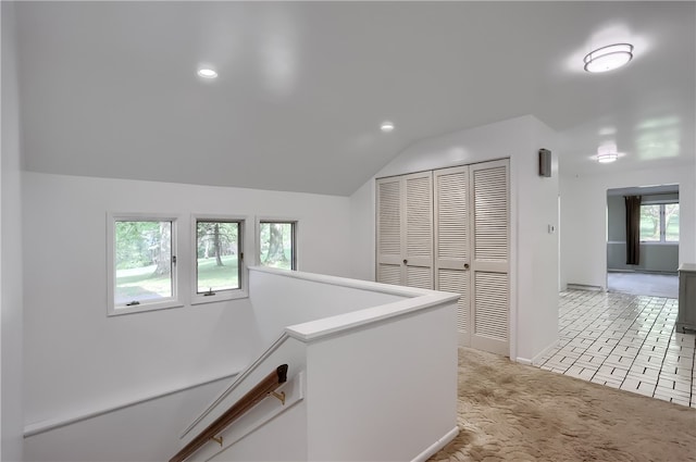 hallway with light carpet and vaulted ceiling