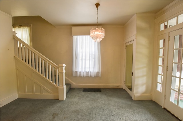 carpeted entryway featuring an inviting chandelier and crown molding