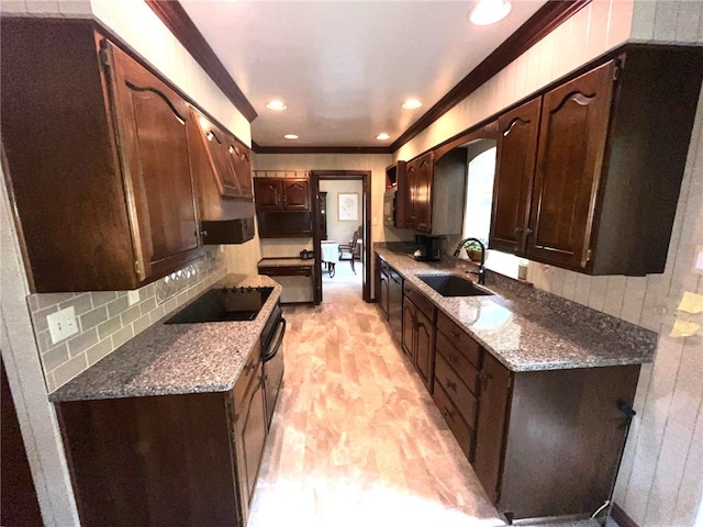 kitchen featuring dark stone counters, light wood-type flooring, sink, decorative backsplash, and dark brown cabinetry