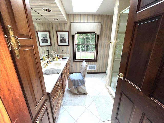 bathroom featuring a skylight, a shower with door, and vanity