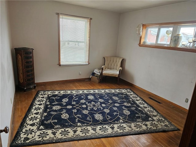 living area featuring wood-type flooring, baseboards, and visible vents