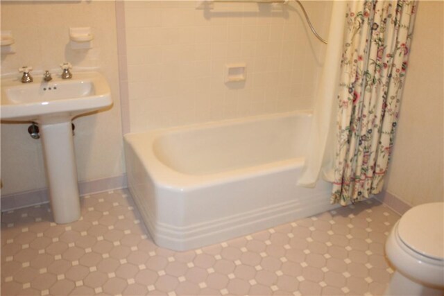 bathroom with shower / bathtub combination with curtain and toilet